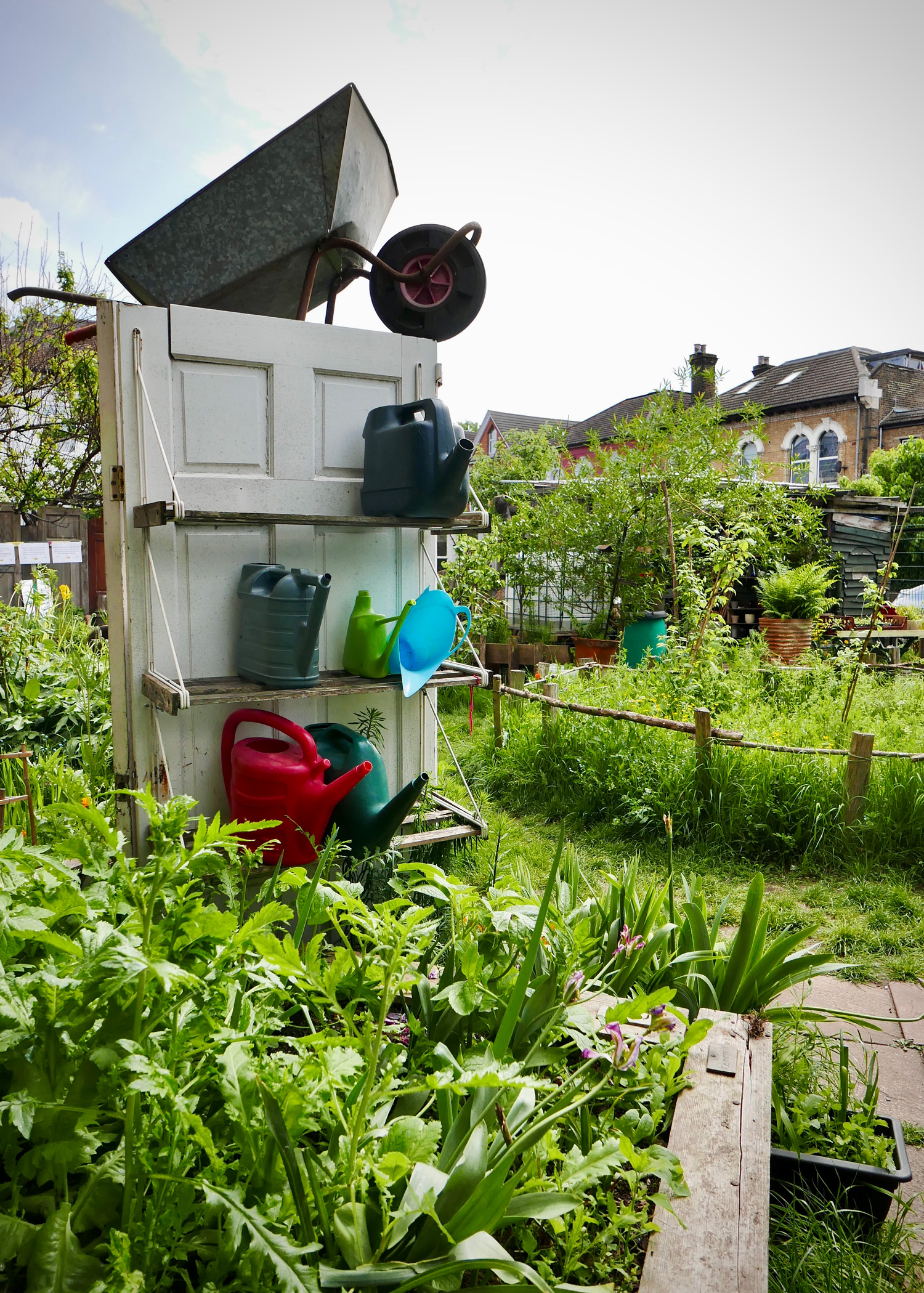 image of recycled door in a garden used as shelves for watering cans